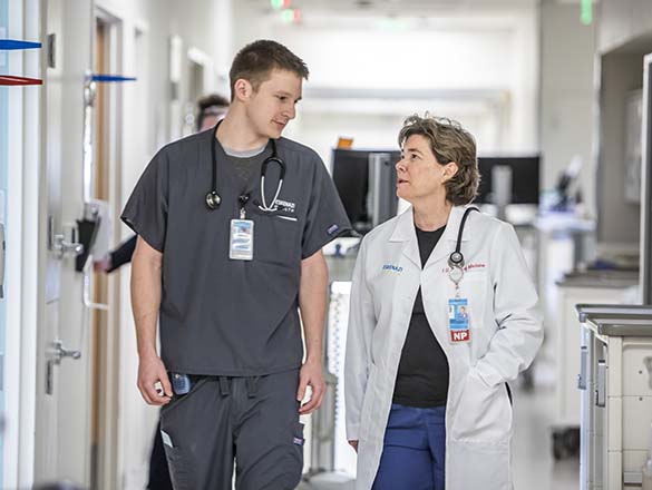 Nurse and doctor walking down a patient hallway talking to each other