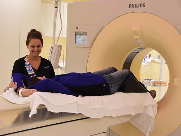 Radiology tech talking with patient laying on a CT table