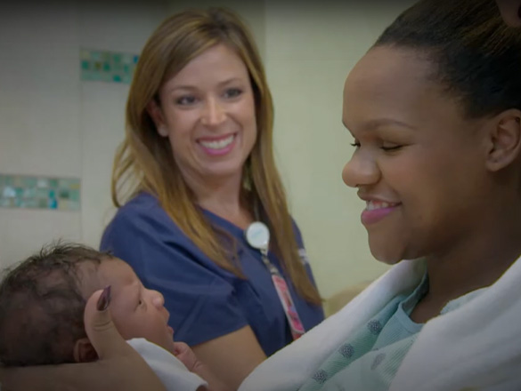 Nurse smiling at mother who's smiling at her new baby