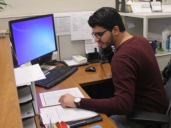 Volunteer doing clerical work at a computer while on the phone