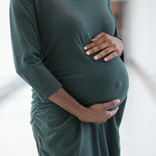 A pregnant person with their hands on their belly
