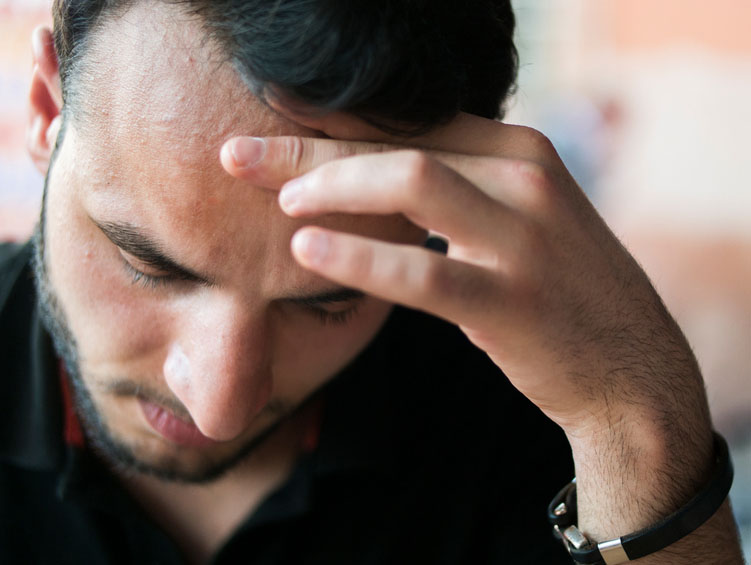 A man holds his hand to his forehead in distress