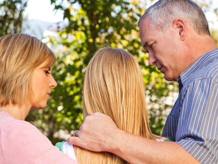 Parents comforting their daughter