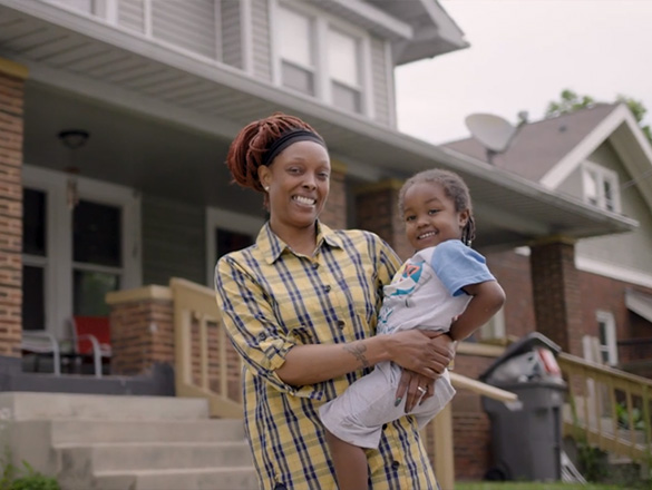 A woman holding her daughter standing outside their home in downtown Indianapolis