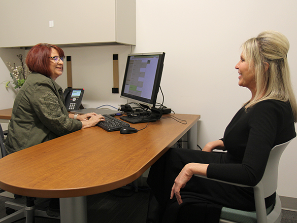 A woman behind a desk talking to a woman sitting in a chair