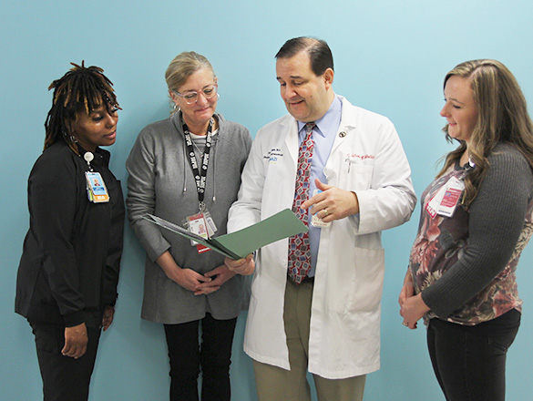 A group of four providers reviewing research data in a folder