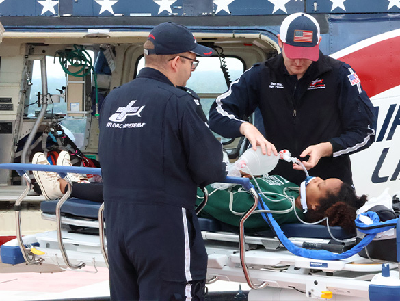 Trauma helicopter medics working on a patient in front of a helicopter